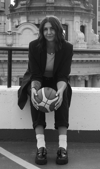 Person holding a basketball on a rooftop with architectural background